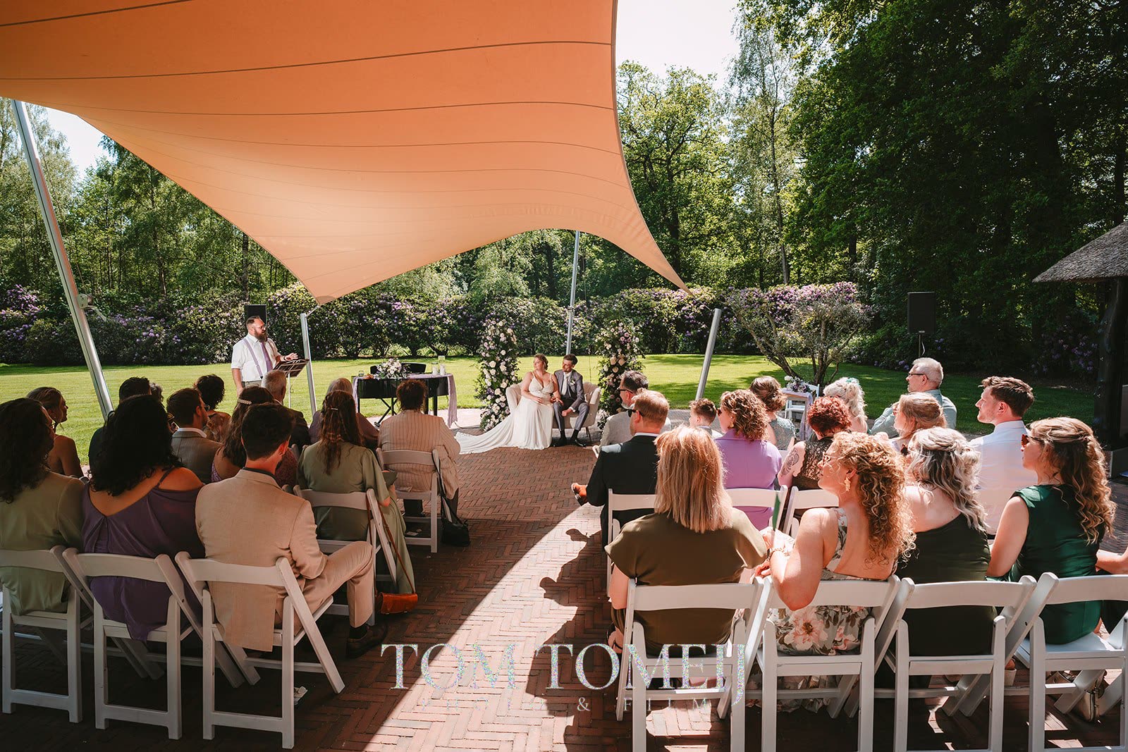 Ceremonie in de tuin onder een oranje zeildoek